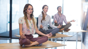 Business people performing yoga on table in office